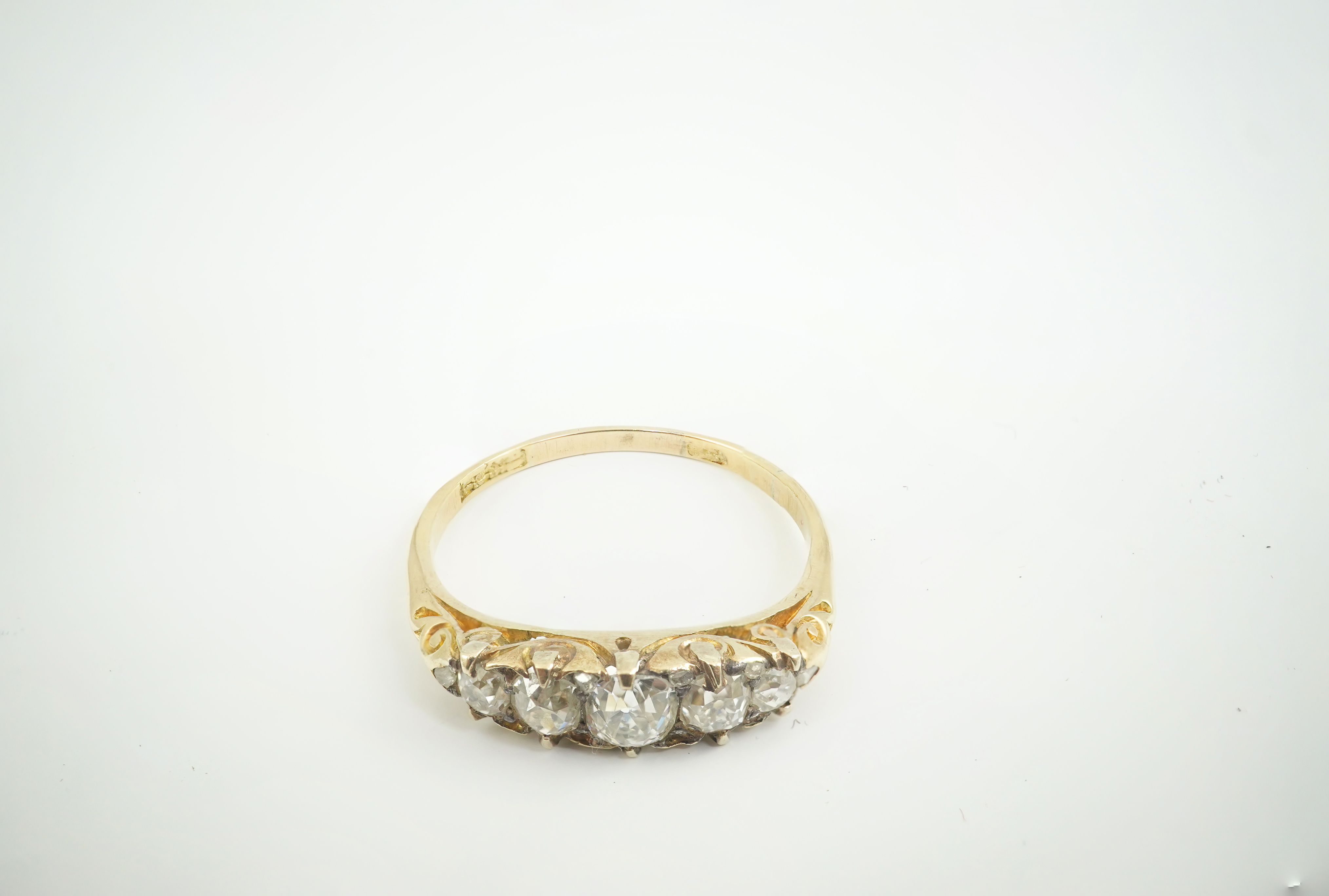 An early 20th century gold and graduated five stone old cut diamond set half hoop ring